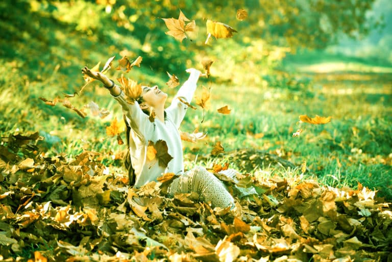 Woman enjoying fallen autumn leaves. Let it Go